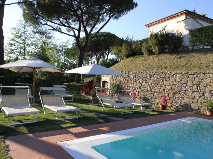 Pool mit Liegen und Sonnenschirmen in Toskana an Villa